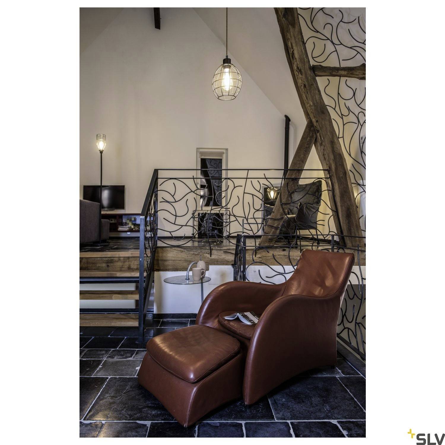 A cosy room with a brown leather armchair, lamps, and wooden beams. A hint of industrial and modern design.