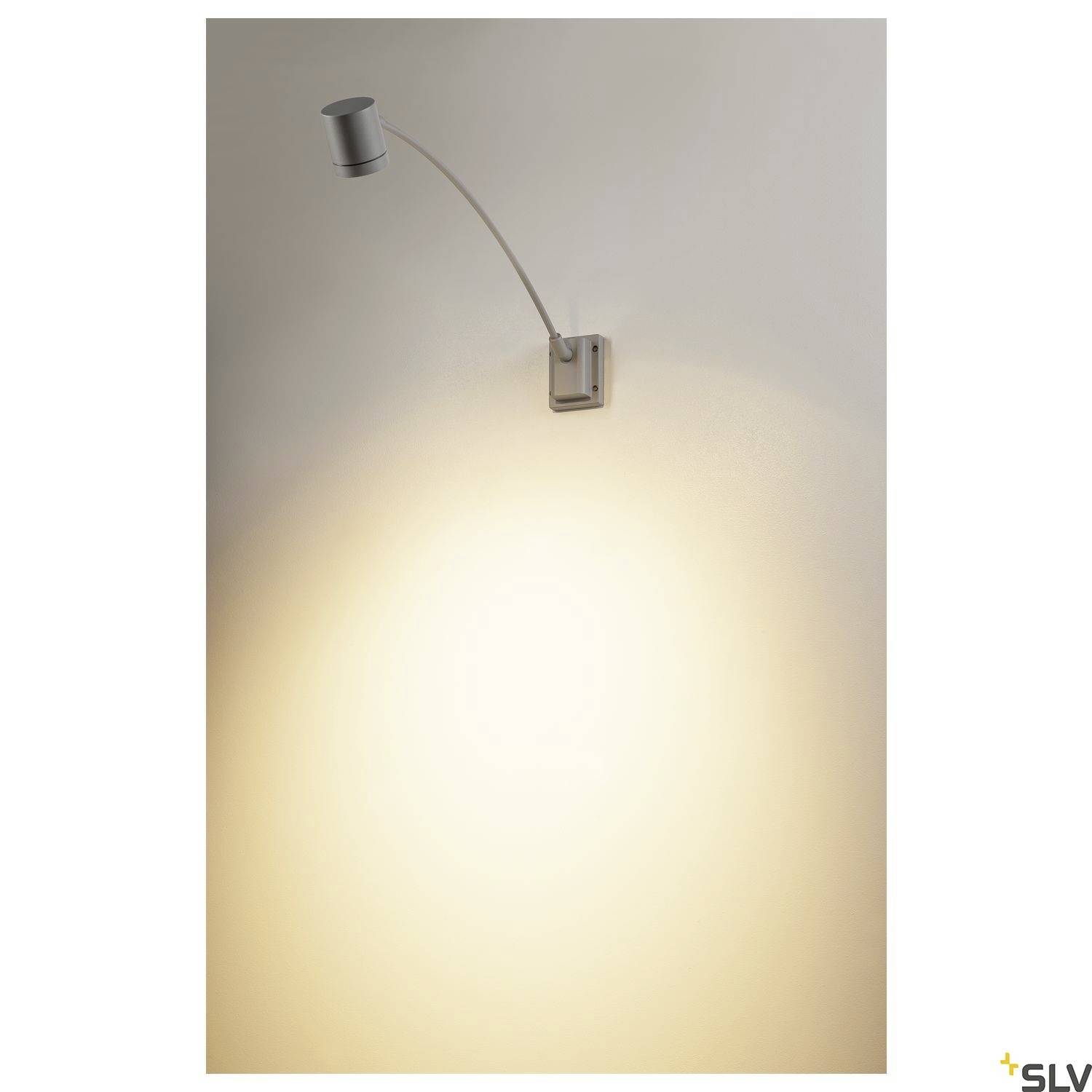A wall light with a pivoting arm illuminates a warm, yellow surface on the wall. Ideal for accent lighting.