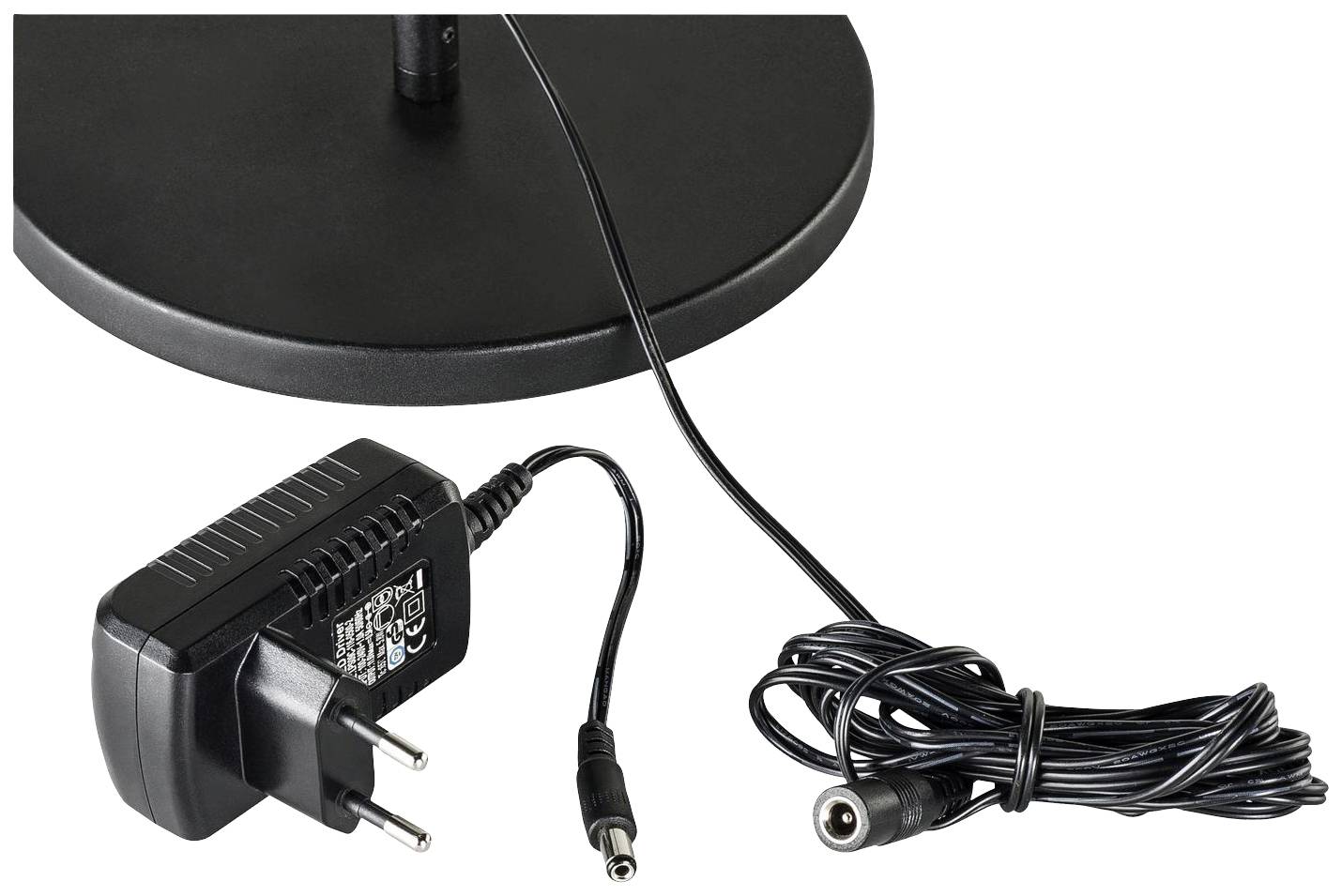 Power supply with European plug, connected to a coiled cable, lying on a table. Suitable for power supply.