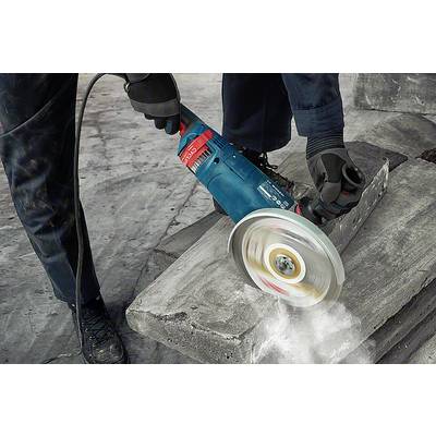 A person is working with an electric grinding machine to sand a stone slab. Sparks and dust are flying around.