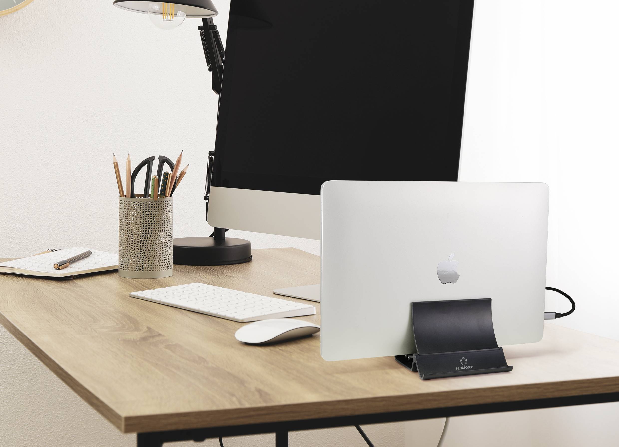 A modern desk with a desktop computer, laptop, keyboard, mouse and pen holder. The room appears minimalist and tidy.