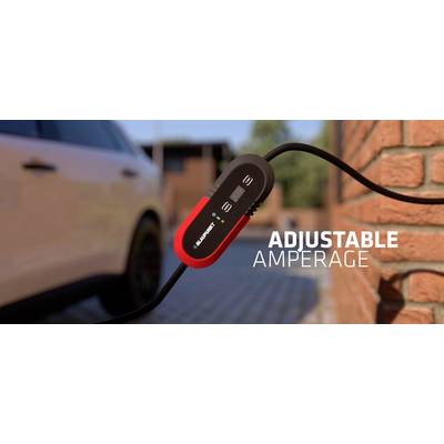 A car charging cable with an adjustable amperage is connected to a vehicle. A brick wall is visible in the background.