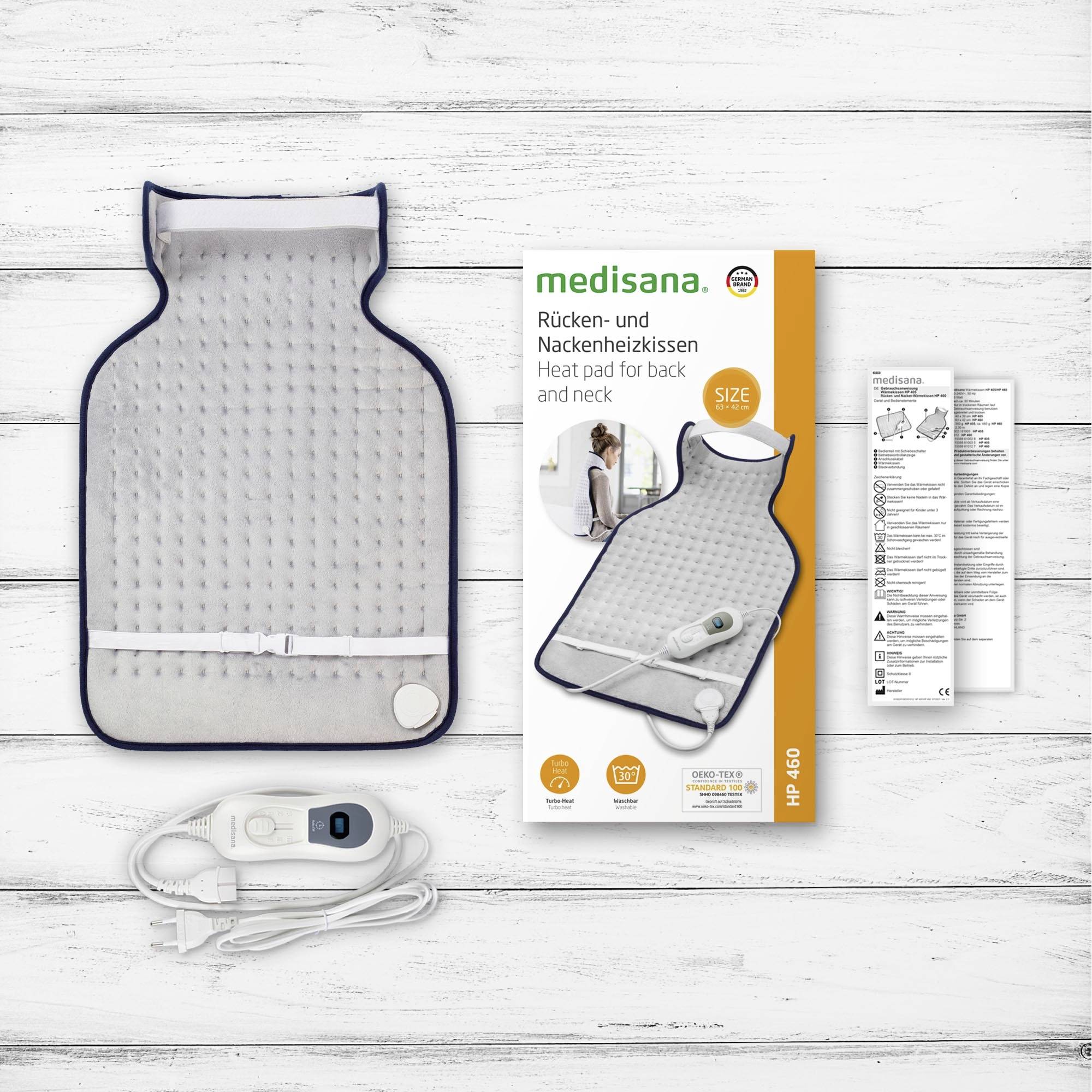 Medisana heating pad for back and neck, pictured with packaging and control unit on a wooden table.