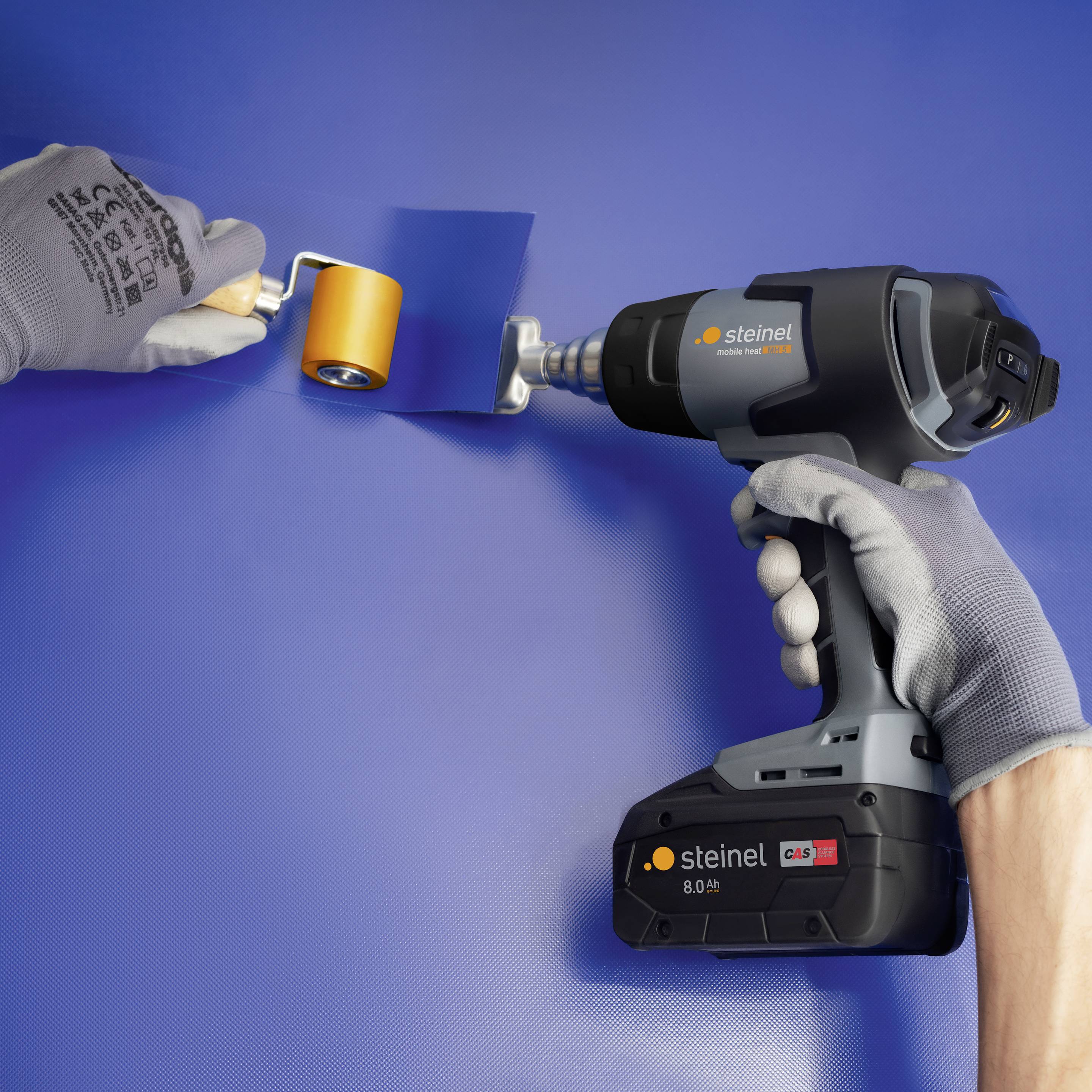 A person is holding a hot air blower in their right hand, while smoothing a film or material with a roller using their left hand.