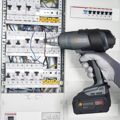 A technician is installing a hot air blower at an open fuse box. The blower displays the 'steinel' logo. Close-up visual detail shot.
