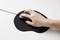 A hand is holding a computer mouse, which is resting on a black mousemat.