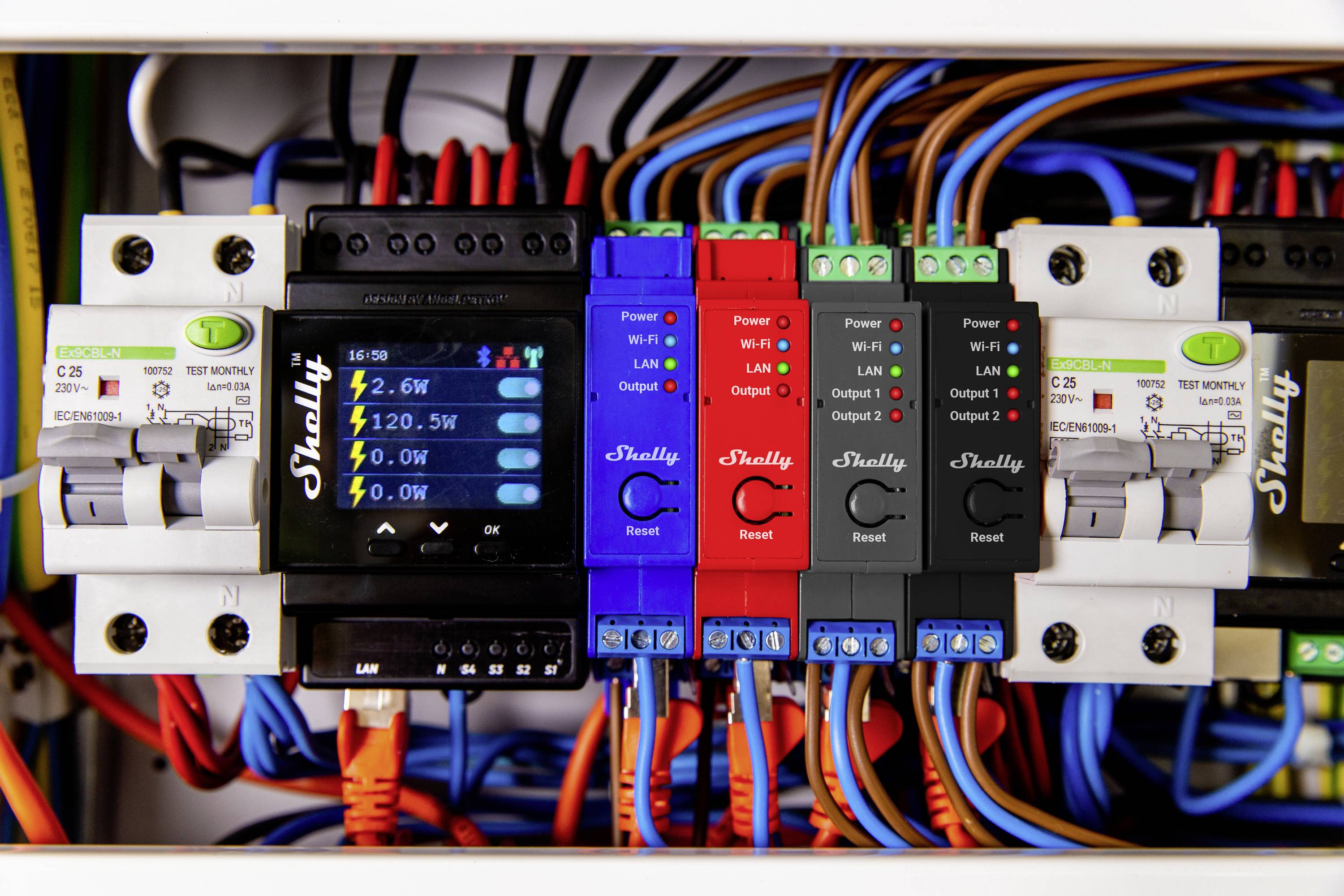 Electrical control panel setup with multiple coloured fuses and wires, displaying active connections and energy values on a screen.