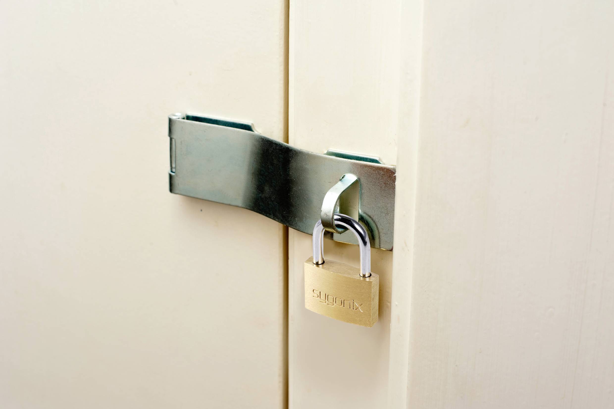 A metal padlock secures a cream-coloured wooden door.