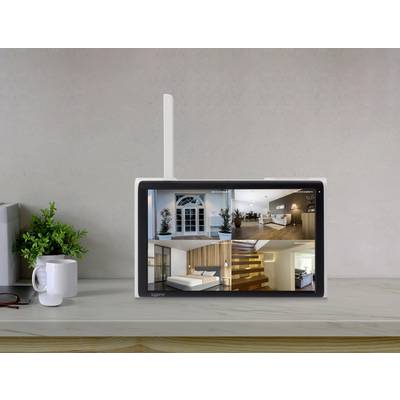 A monitor on a table displays security camera images of various rooms in a house. Next to it are a cup and a plant.