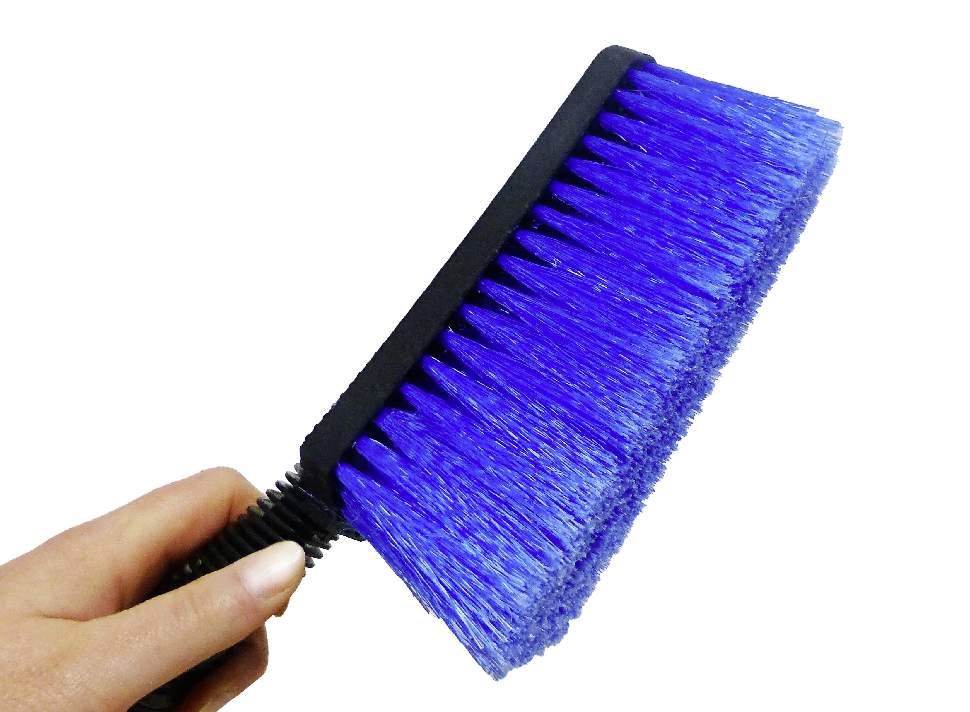 A blue cleaning brush is being held by a hand. The bristles are dense and straight. Ideal for clean surfaces.