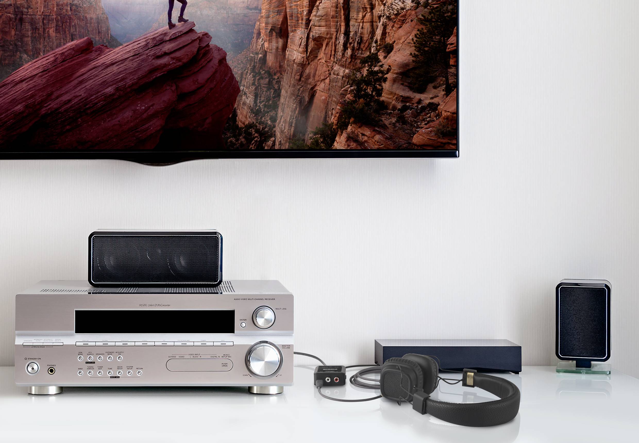 Living room with entertainment electronics: an amplifier with speakers, headphones and a television showing a mountain landscape image.