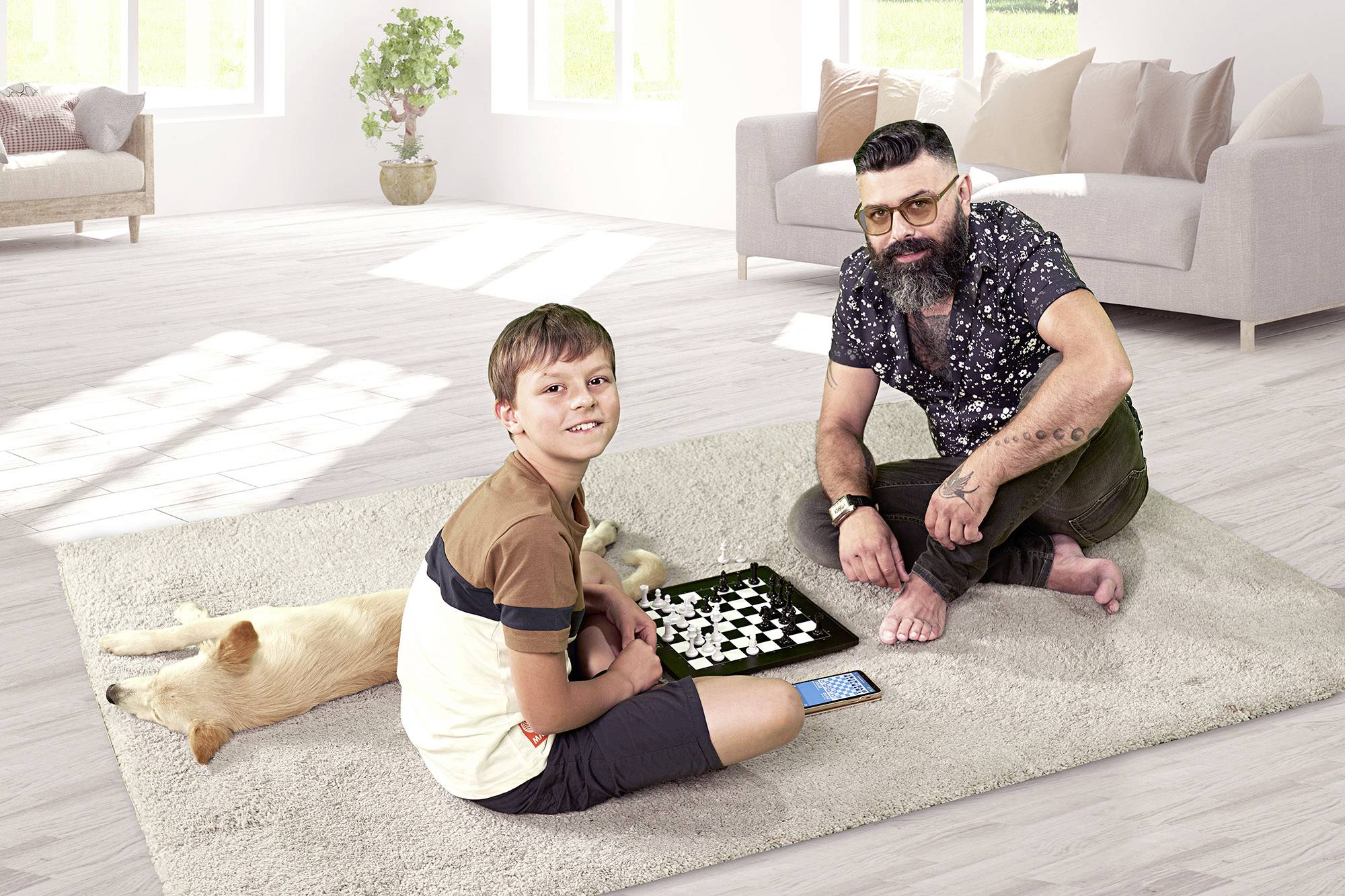 A man and a boy are playing chess on a light-coloured carpet in a living room. A dog is sleeping beside them.