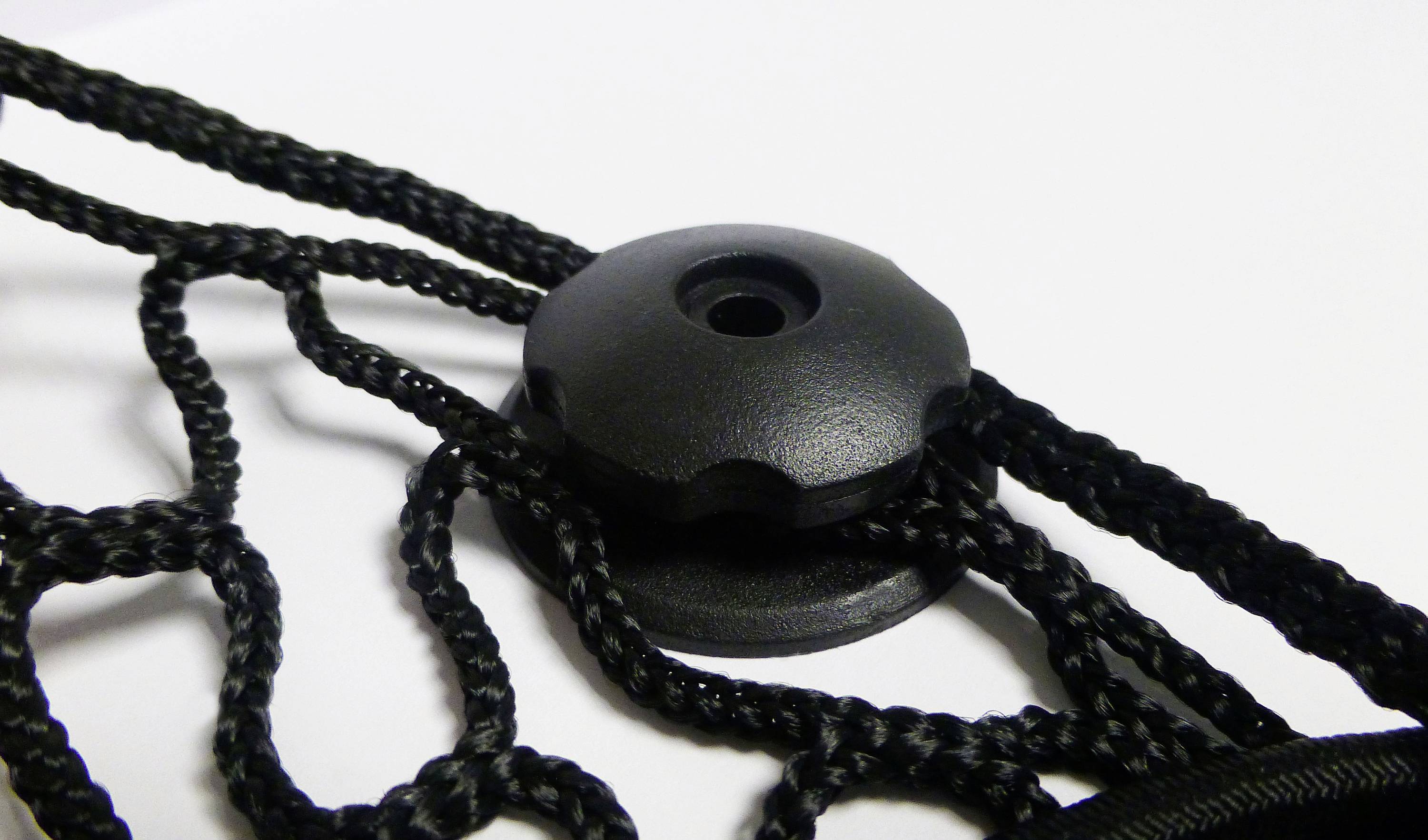 A black cord stopper holds several braided black cords together against a white background.