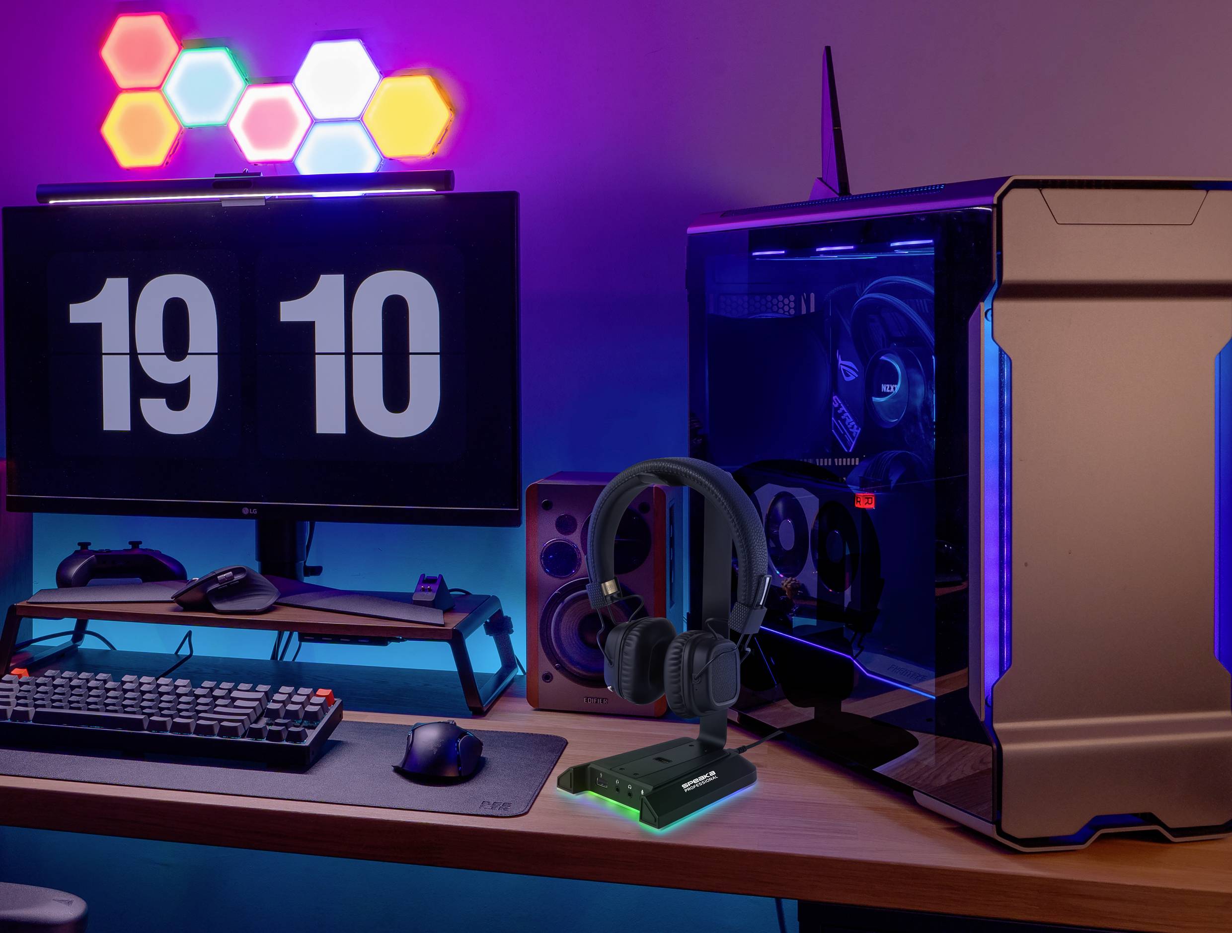Gaming setup with a monitor, PC tower, illuminated keyboard, and headset. LED lights in the background with a clock display showing '19:10'.