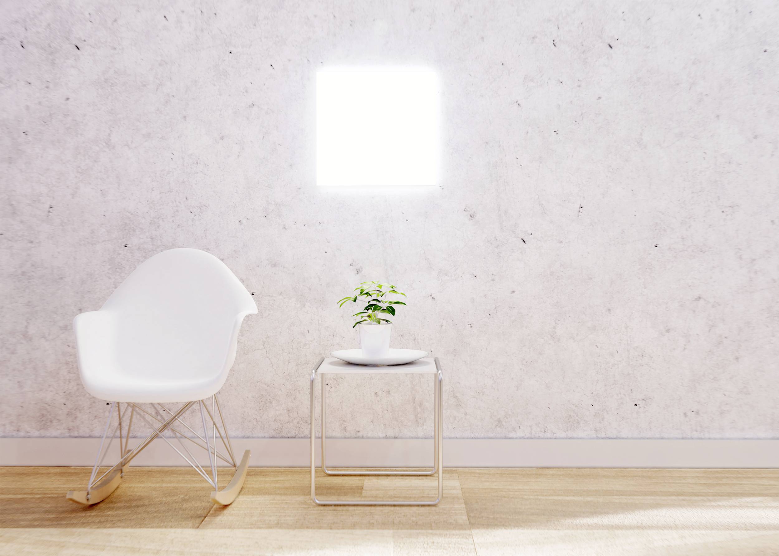 White rocking chair and small table with potted plant in front of a light wall in a minimalist room.