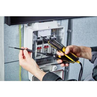 'Person tests voltage at an open fuse box with a measuring device.'