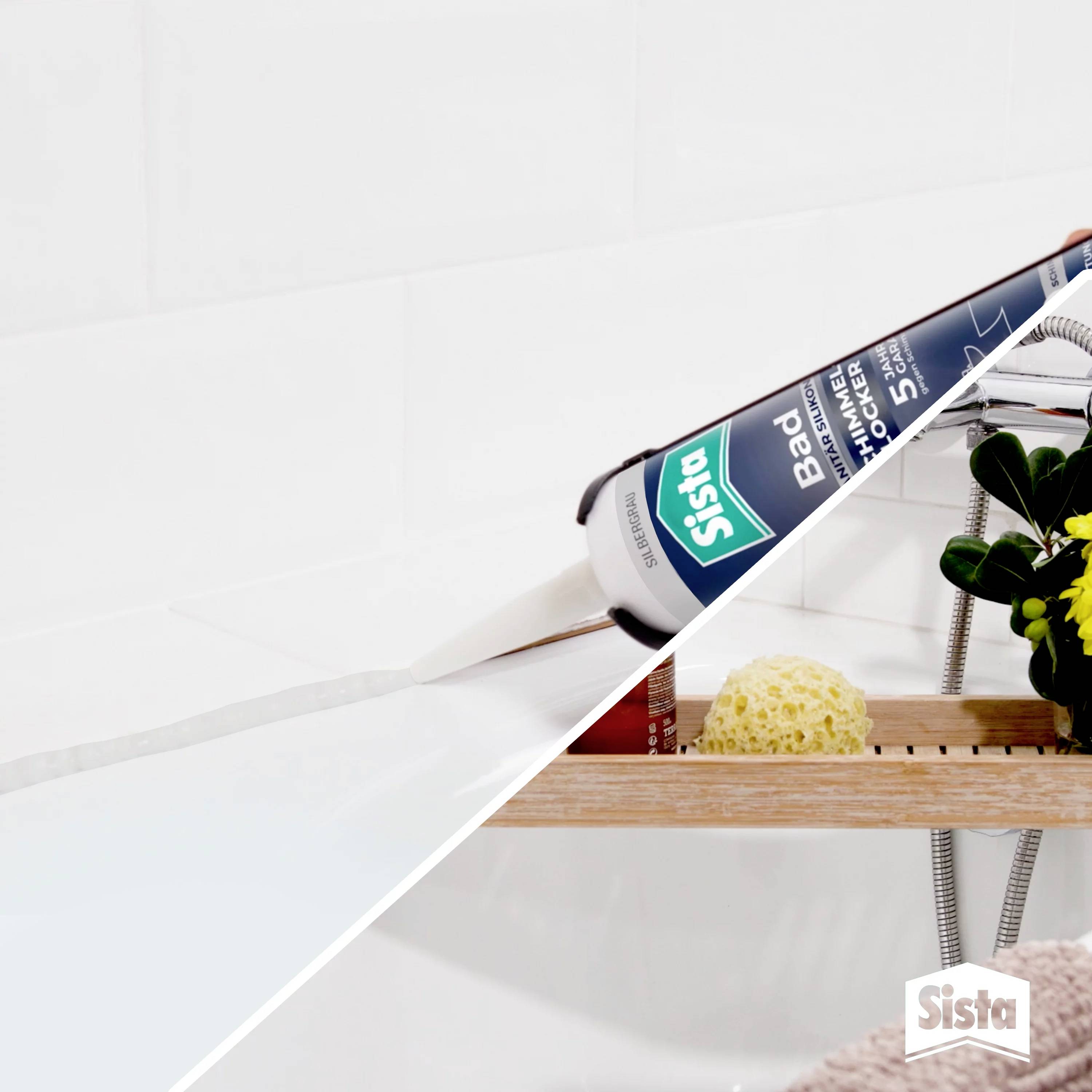 A tube of Sista bathroom silicone is being applied to a tile joint in the bathroom. A wooden shelf with shower accessories lies to the right.