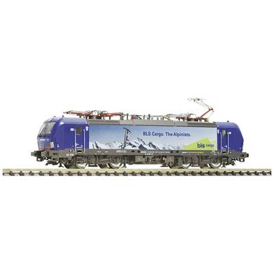 Freight train locomotive with blue BLS Cargo livery and mountain motif, travelling on railway tracks.