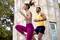 A woman and a man are doing fitness exercises outside next to a stone column. They are wearing sports clothing and appear focused.