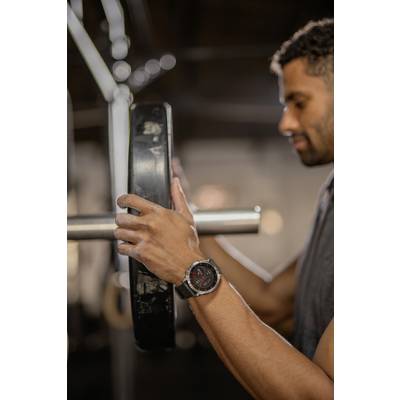 A person in the gym is placing a weight on a barbell. The focus is on the hands and the weight.