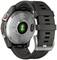 A smartwatch with a black strap and circular metal casing, with a heart rate sensor and charging port on the back.