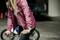 A woman wearing a pink jacket is cycling in an urban environment. She has a wristwatch on her wrist.