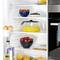 A fridge with open doors. Inside are oranges, strawberries, blueberries, eggs, a carafe of orange juice, and a large water jug.
