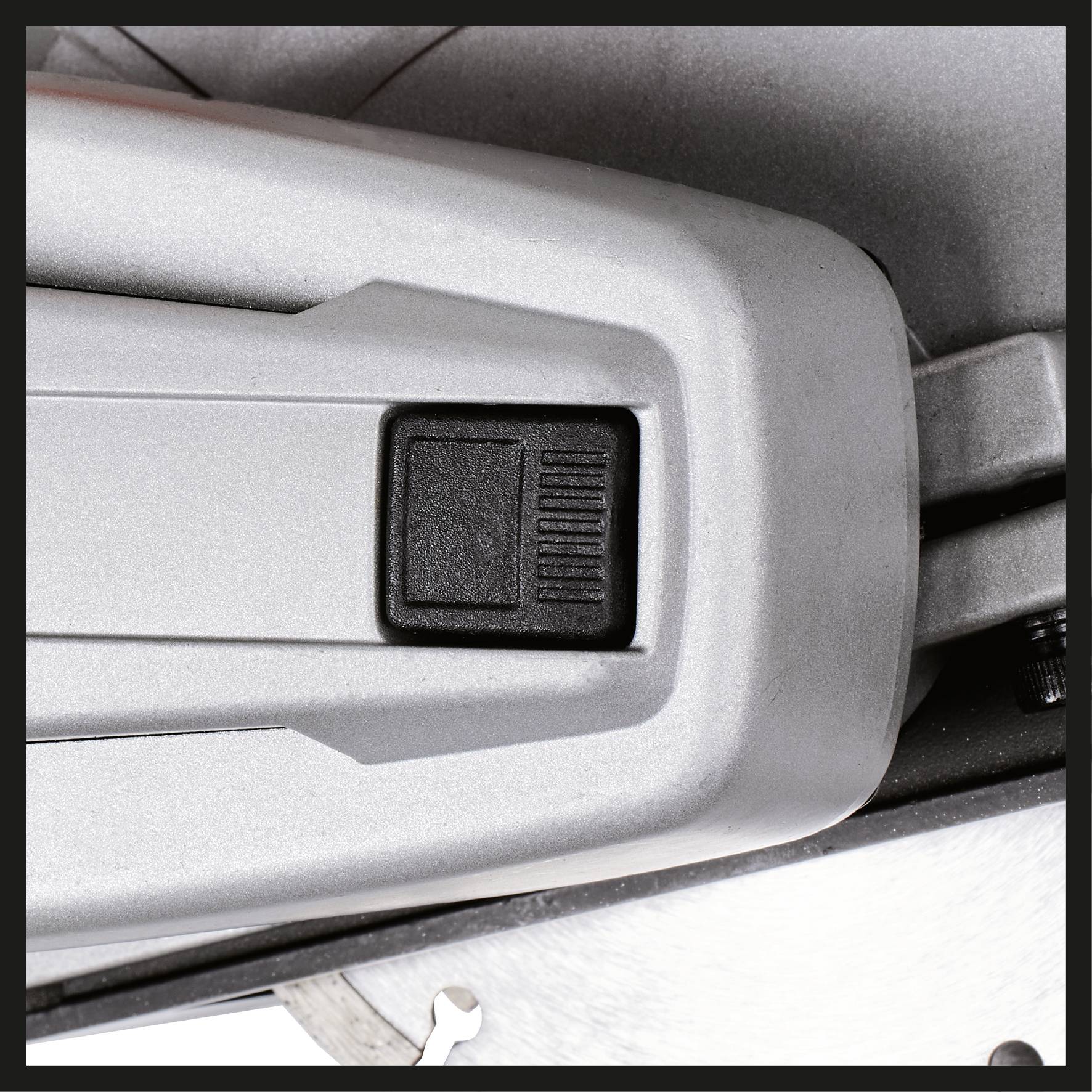 A silver, rectangular casing with a black button is depicted. The button has fine grooves for better grip.