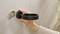 A hand is mounting a black holder on a grey wall, presumably for a bathroom accessory such as a tumbler or soap dispenser.