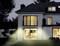 Two-storey modern house at dusk, with illuminated interior and well-maintained garden.