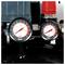 Two pressure gauges on industrial equipment display readings in bar and psi, with one larger gauge and one smaller gauge рядом a red fitting.