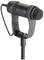 A black, wired microphone with a mesh head, mounted on a stand, against a white background.