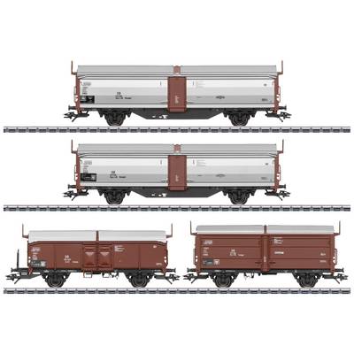 Four freight train wagons on parallel tracks. Each wagon is painted differently, two in red and two in grey-red.