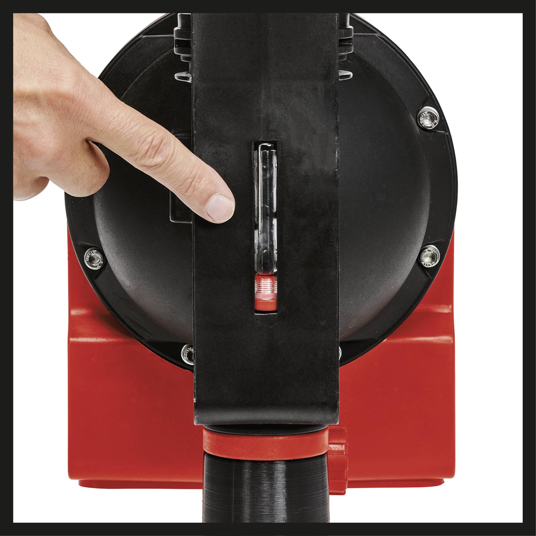 A hand is pointing at a measuring device on a red piece of equipment, indicating that the level has been reached.
