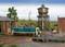 A model railway scene with a green locomotive on a track, surrounded by a railway shed, water tower, and landscape.
