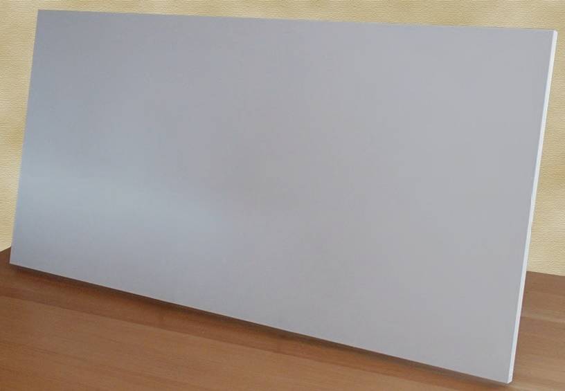A rectangular white plate stands at an angle on a wooden table, in front of a beige wall.
