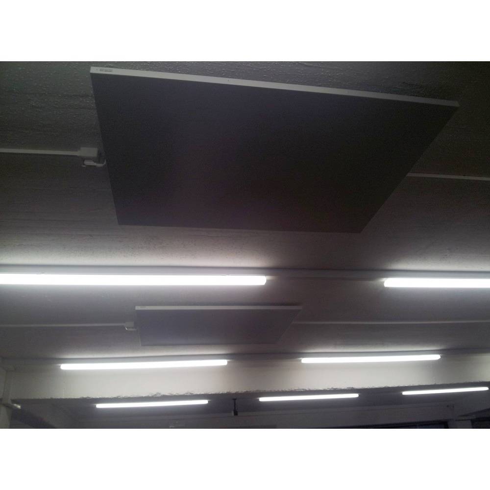 Several rectangular black heating panels on a ceiling of a room, surrounded by neon tubes in an industrial setting.