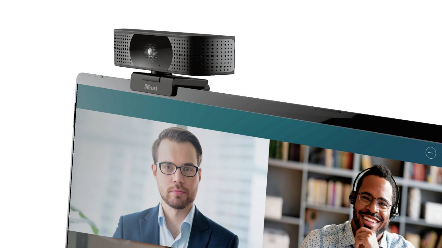 A webcam is mounted on a laptop, with a video call featuring two people displayed on its screen.