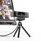 A webcam on a tripod is positioned in front of a monitor displaying a video conference with two participants.