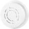 A white smoke detector with round openings on the front, mounted on a ceiling for early fire detection in indoor spaces.