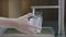 A hand is filling a transparent carafe with running water from a kitchen tap.