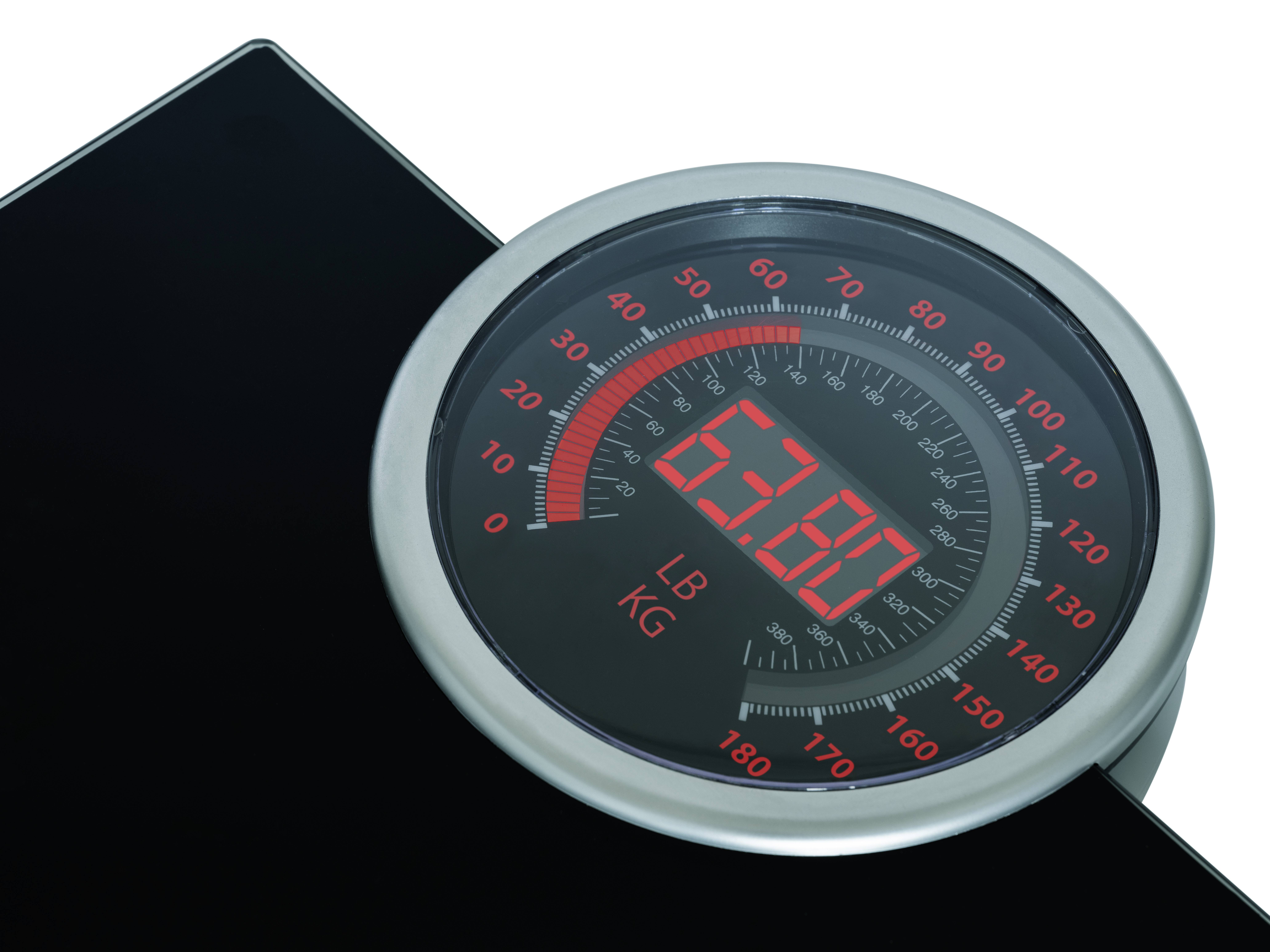 Display of a scale showing a weight of 63.8 kilogrammes. Digital readout in red indicates weight. Scale in kilogrammes and pounds clearly legible.