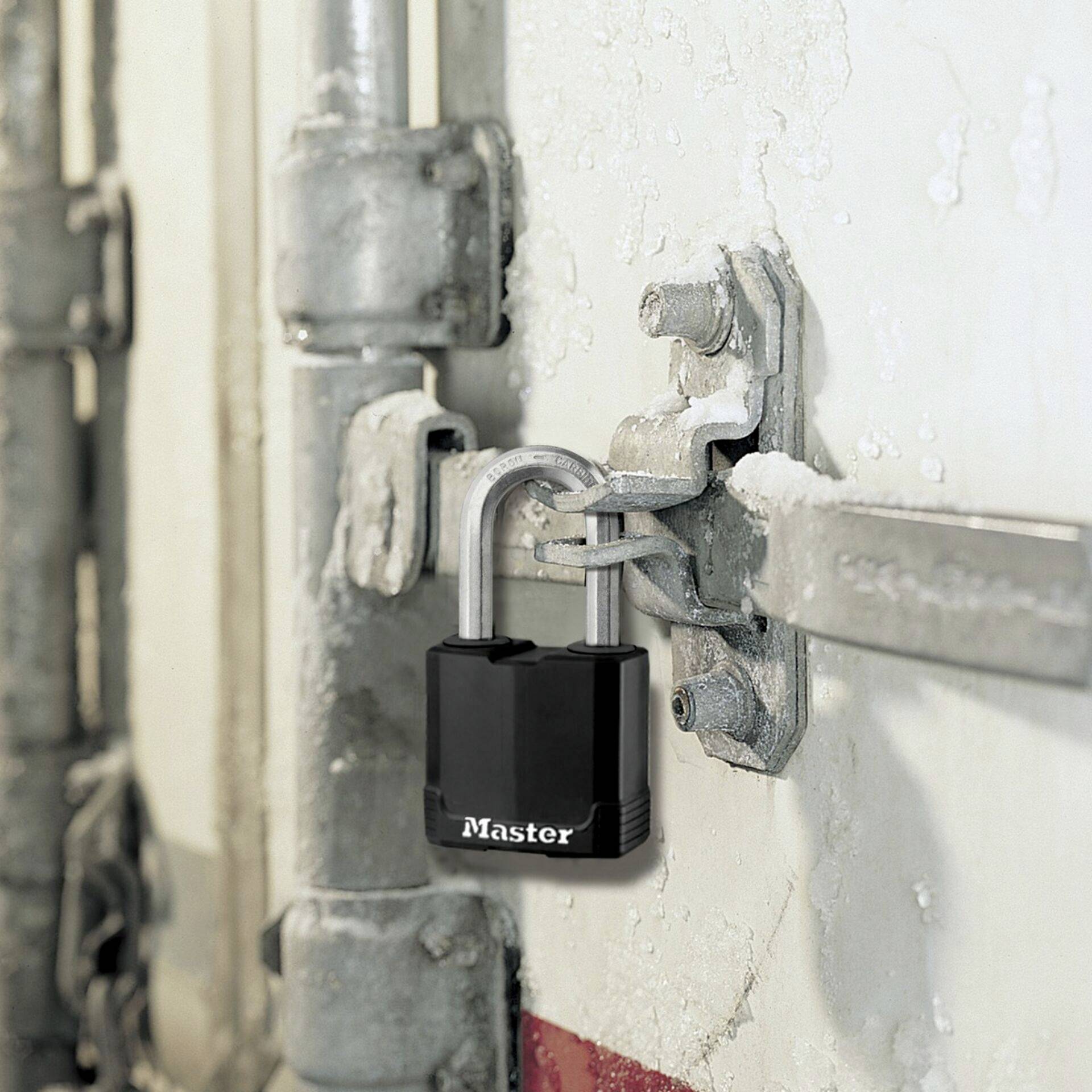 A black padlock secures a metal door bar. The lock bears the inscription 'Master'. The surroundings are industrial.