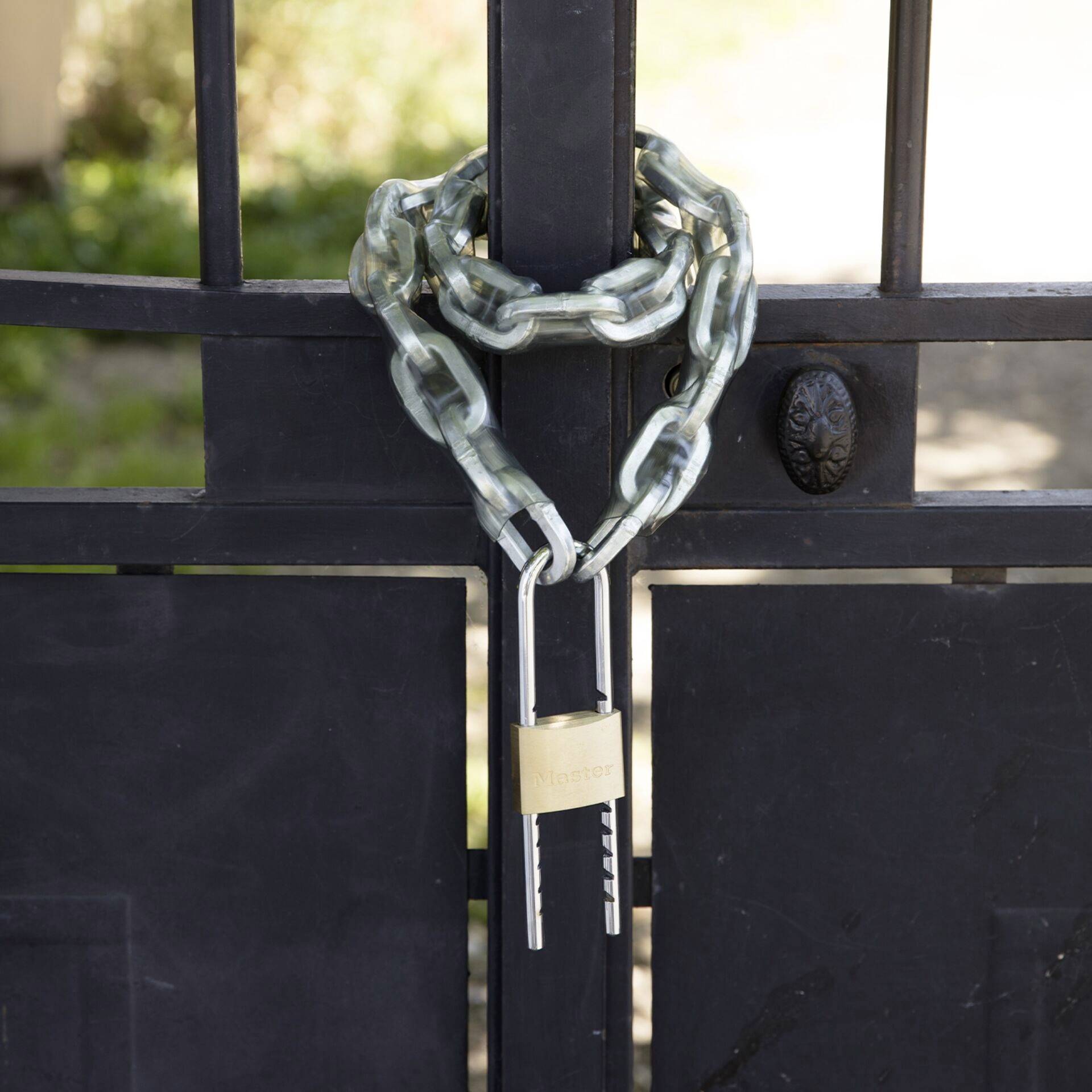 A black gate is secured with a heavy metal chain and a padlock, indicating limitation or protection.