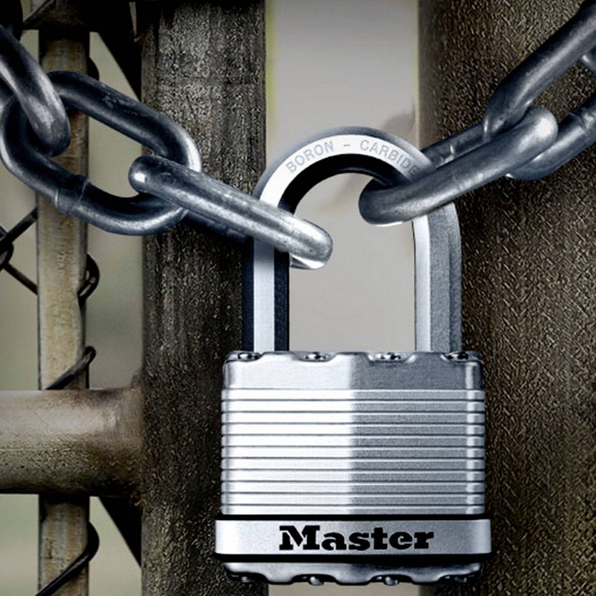 A silver padlock with the inscription 'Master' secures a metal chain to a fence.