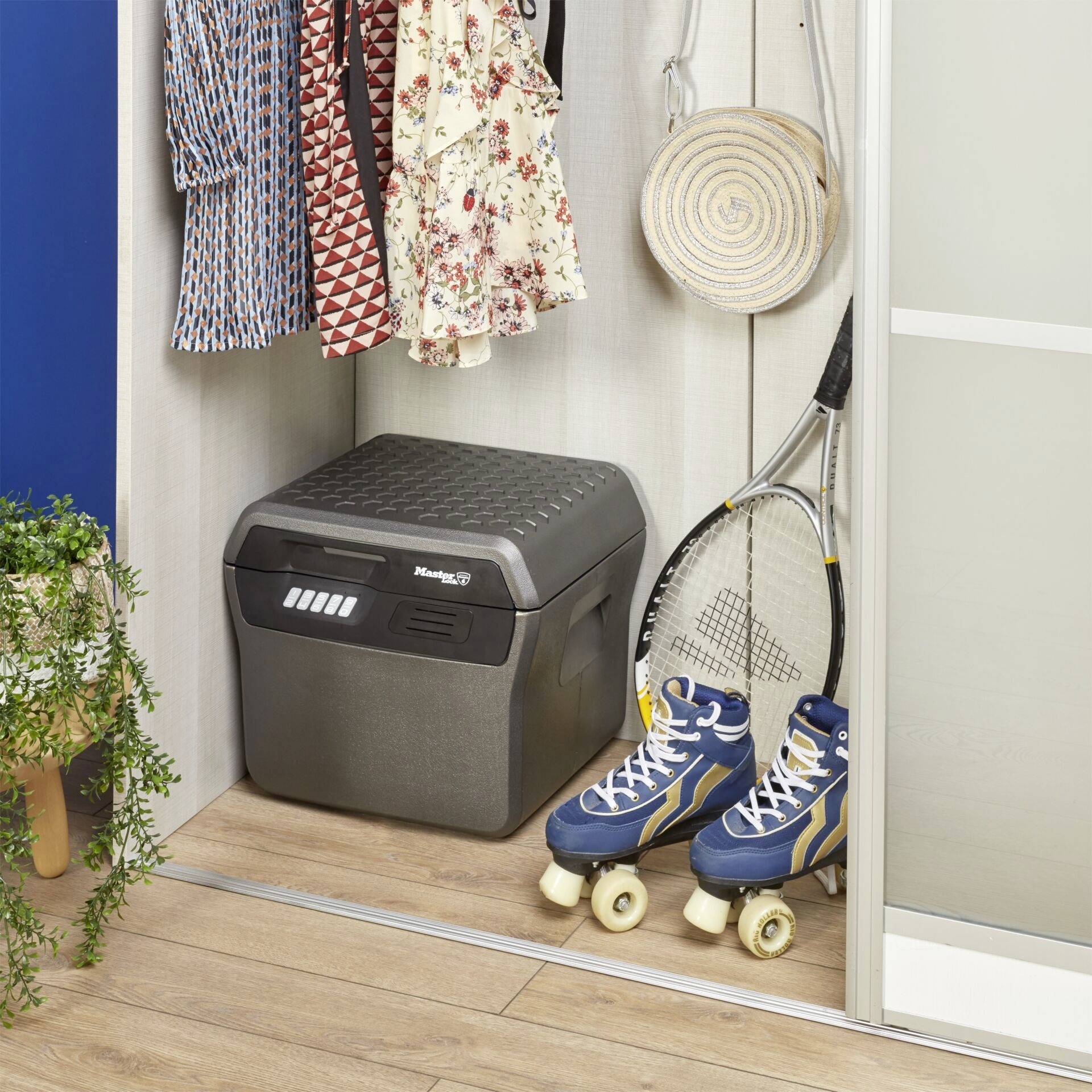 A wardrobe with a blue fridge, tennis racket, roller skates and colourful clothing. A plant stands beside it.