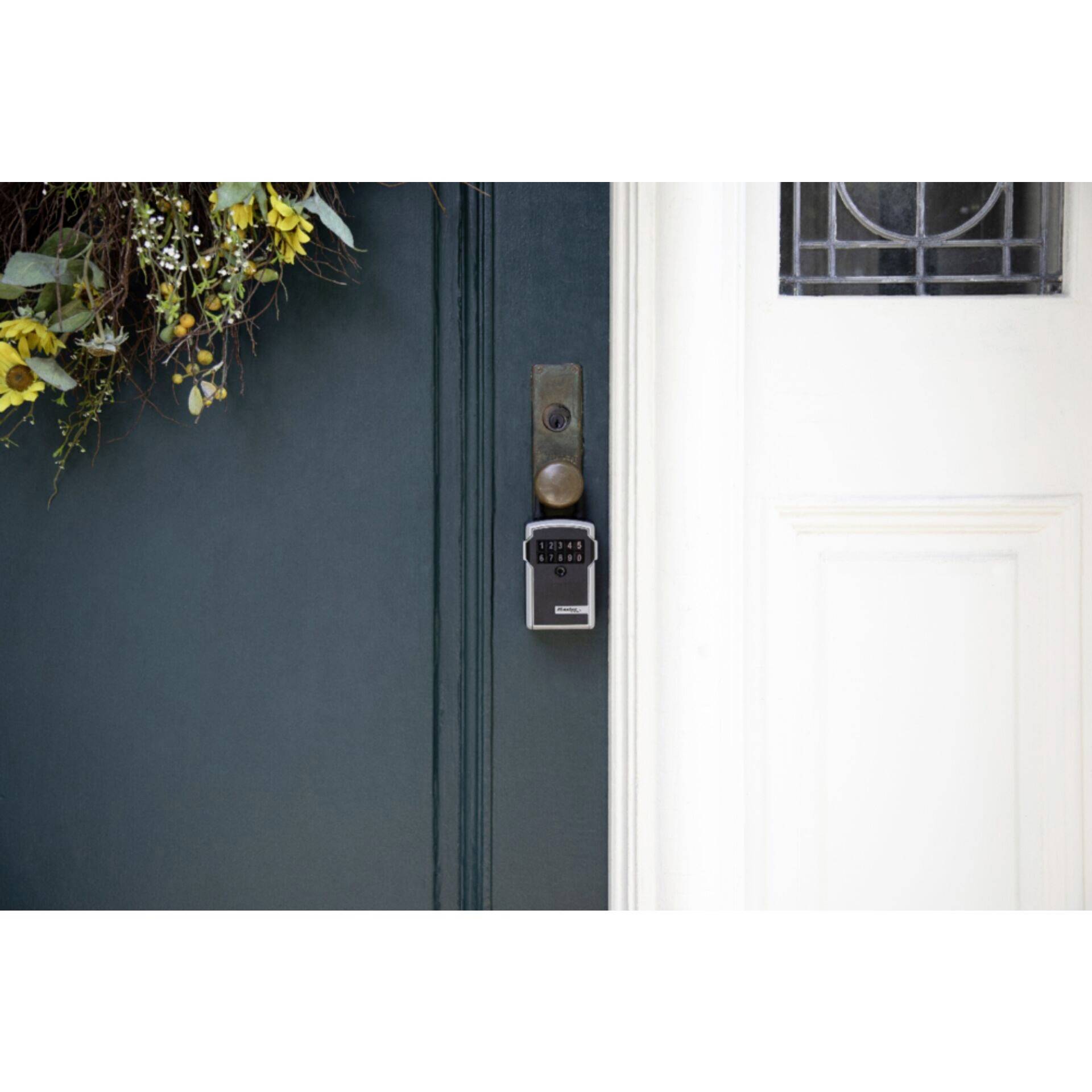 Green door with digital door lock and floral wreath.