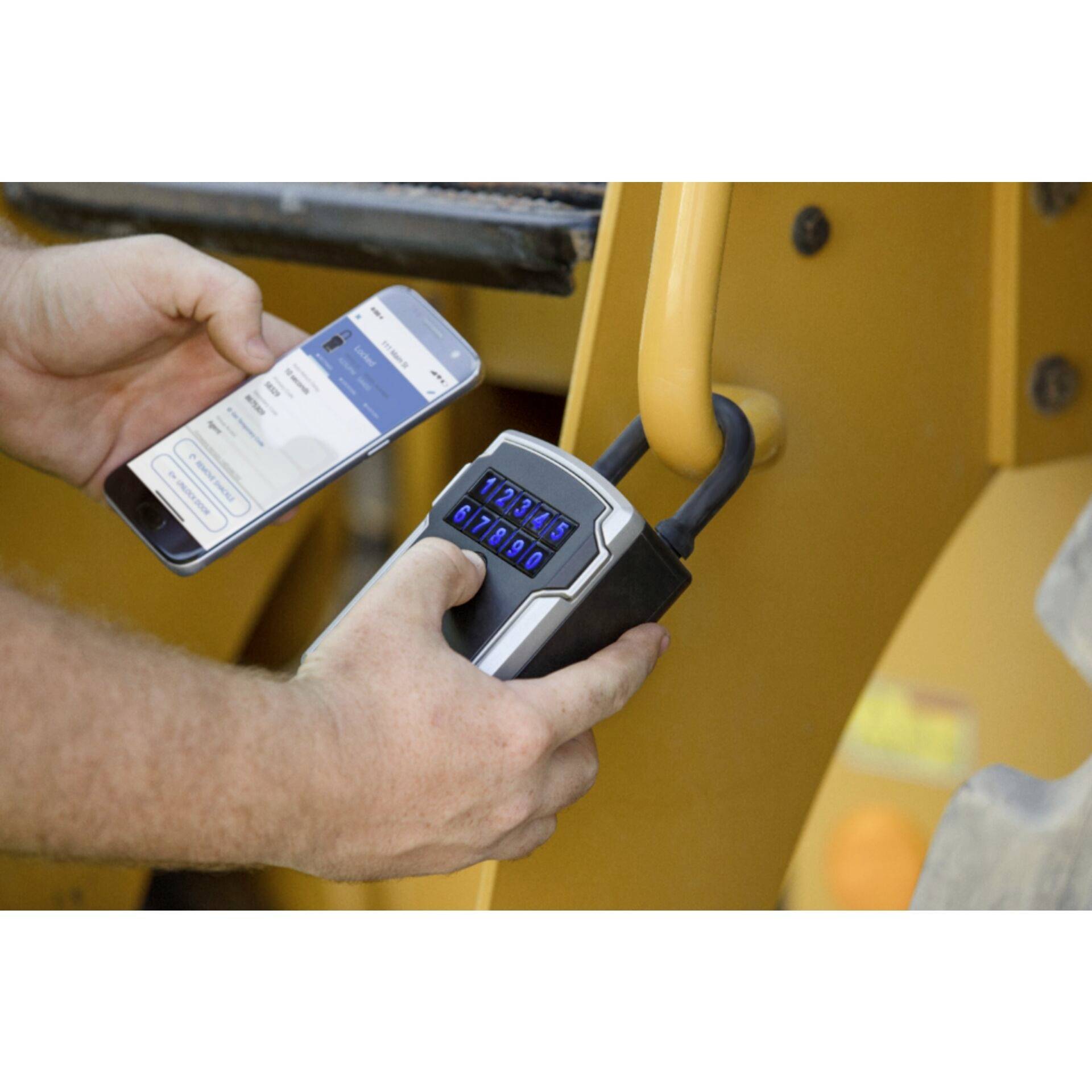 A person is holding a smartphone and unlocking a padlock with a digital keypad. The lock is attached to a yellow railing.