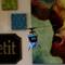 A small blue model helicopter hovers in a room, surrounded by blurred wall decorations in the background.