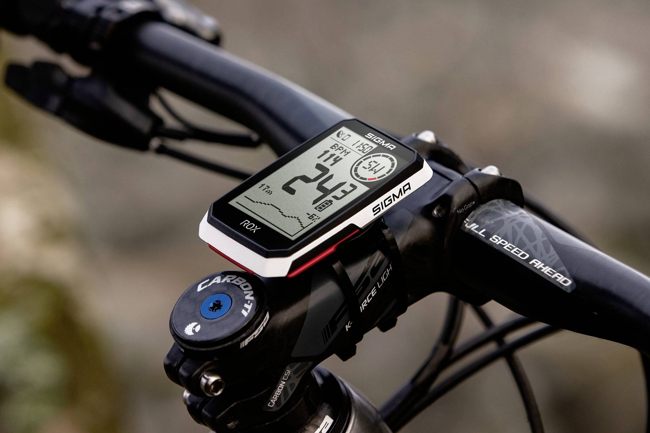 A GPS bicycle computer on the handlebars of a bicycle displays data such as speed, distance, and time. Background blurred.